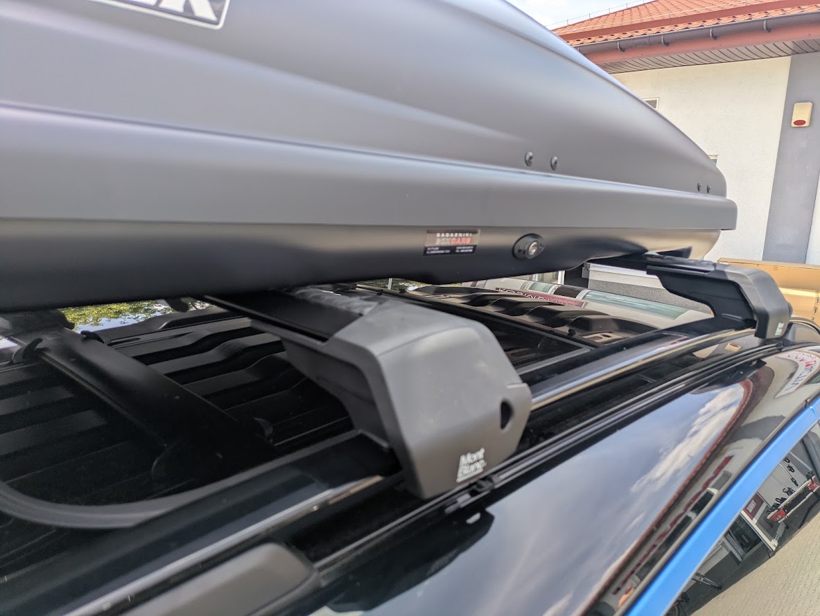 Zbliżenie stóp Mont Blanc Xplore obejmujących szerokie relingi Lynk & Co 01 pod boxem Traxer 6.6