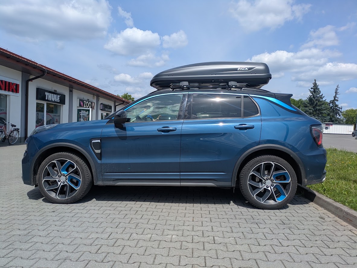 Niebieski Lynk & Co 01 z boxem Inter Pack Traxer 6.6 na belkach Mont Blanc Xplore ? widok z boku