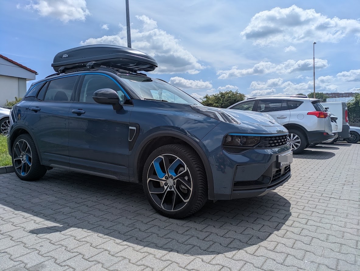 Niebieski SUV Lynk & Co 01 z boxem dachowym na parkingu BoxCars