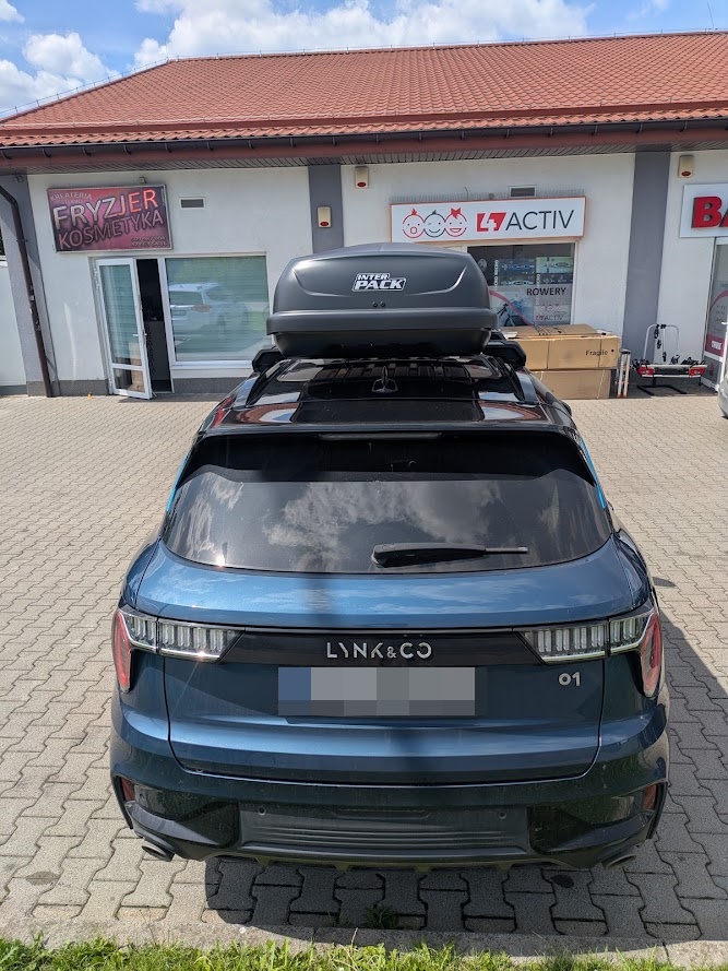 Tył Lynk & Co 01 z boxem dachowym przed sklepem BoxCars w Łodzi