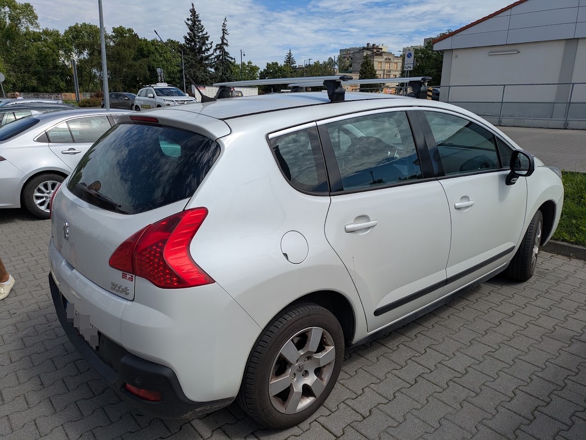 Biały Peugeot 3008 pierwszej generacji z bagażnikiem dachowym Mont Blanc ? widok od prawego tylnego narożnika